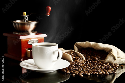 Cup of coffee with saucer,bag,coffee beans on black