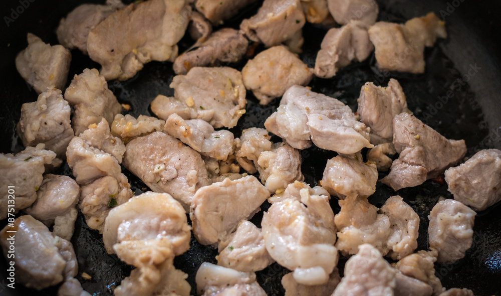 Fried meat with garlic on a pan. Selective focus with shallow depth of field.