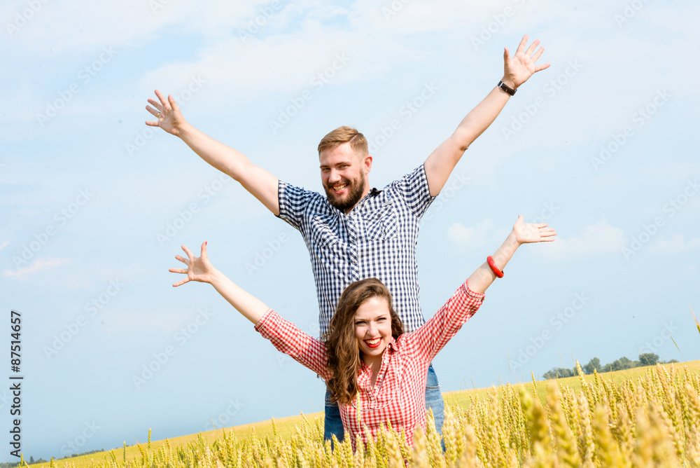 Happy young adult couple in love spending time on the field on sunny day outdoors. Handsome man and beautiful woman standing and kissing. Enjoying holiday together. Romance and love concept Happy young adult couple in love spending time on the field on sunny day outdoors. Handsome man and beautiful woman standing and kissing. Enjoying holiday together. Romance and love concept