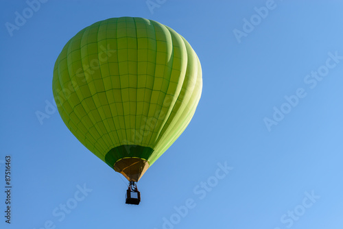 Green hot air balloon in blue sky