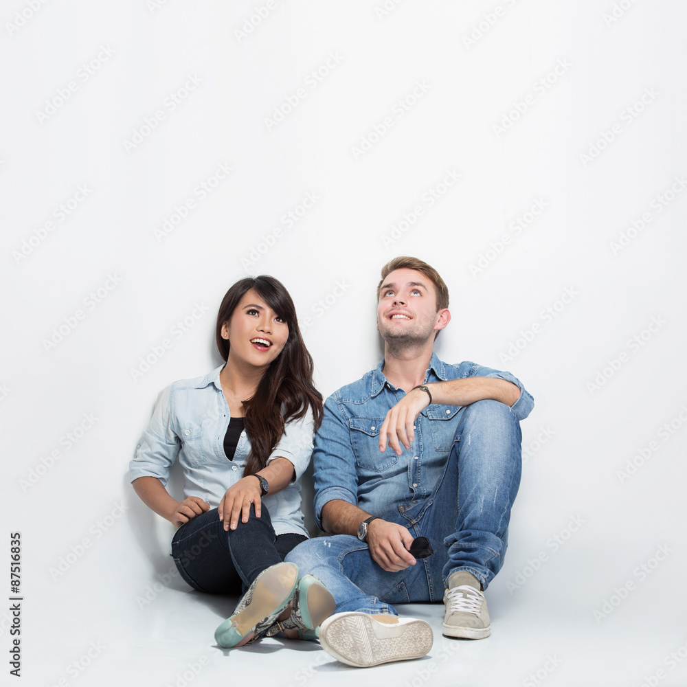 Mixed race couple thinking looking up and sitting on the floor Mixed race couple thinking looking up and sitting on the floor