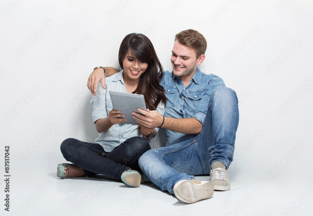Mixed couple sitting on the floor while watching something in a Mixed couple sitting on the floor while watching something in a