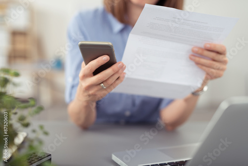 Obraz na płótnie frau schaut auf einen brief und tippt auf ihr mobiltelefon