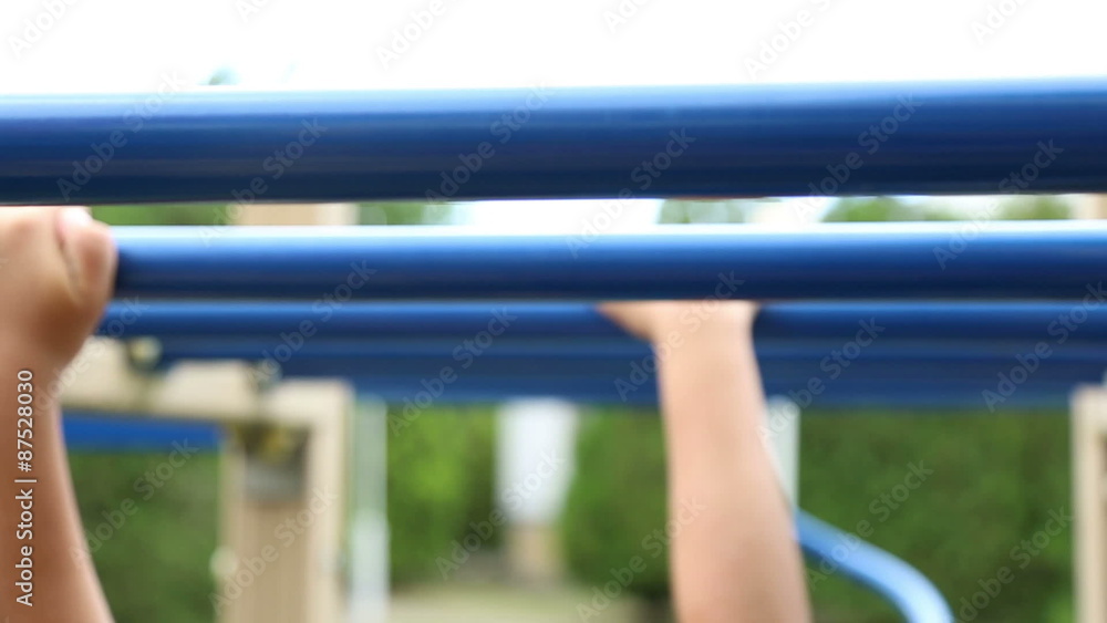 The boy clings to a horizontal bar, performs athletic exercise
The boy clings to a horizontal bar, performs athletic exercise