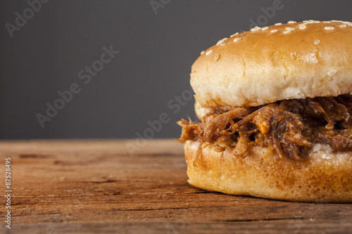 Pulled pork in a bun shot front on on wood with grey background