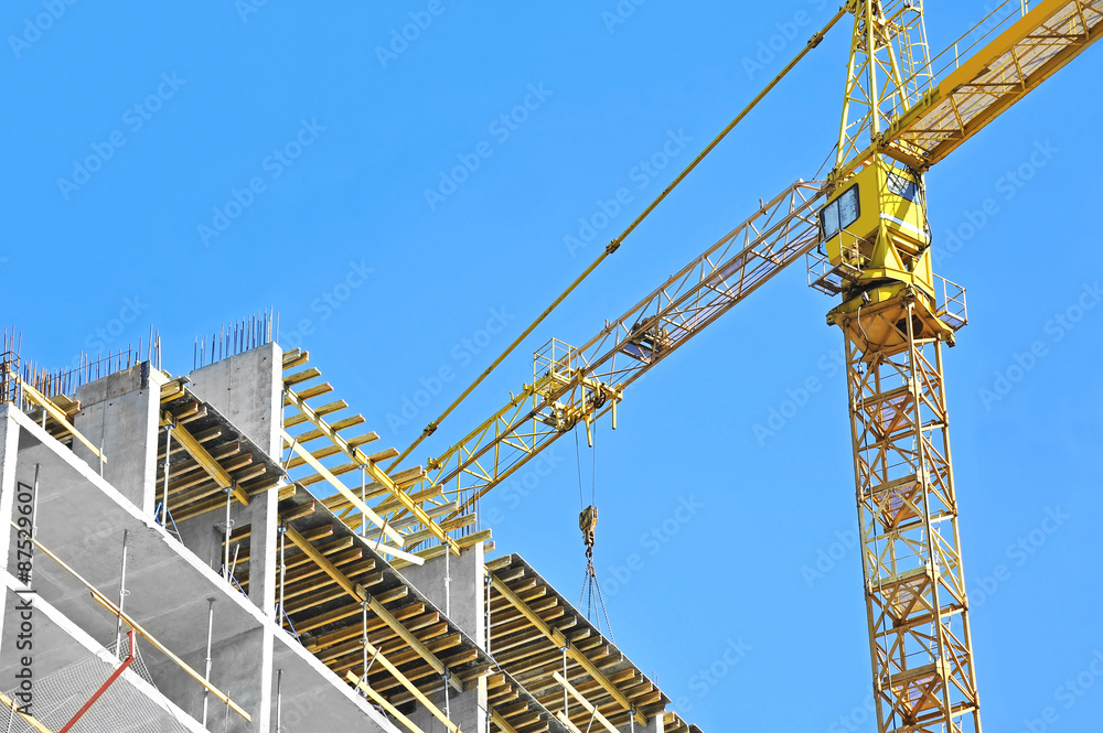 Crane and building construction site against blue sky Crane and building construction site against blue sky