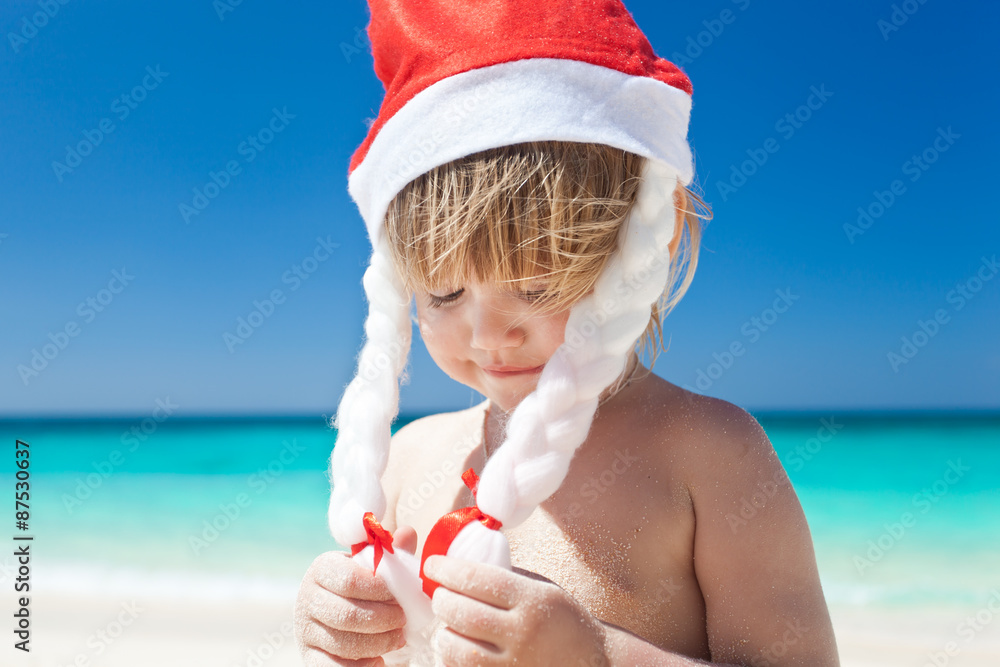 Obraz premium Сute little girl in Santa hat on beach