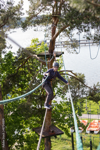 teenager climbing a rope park, boy climbing in adventure park 
