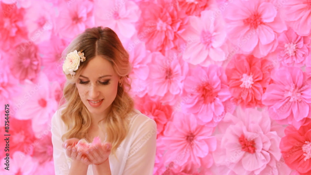 Beautiful woman blowing rose petals on flower background Beautiful woman blowing rose petals on flower background