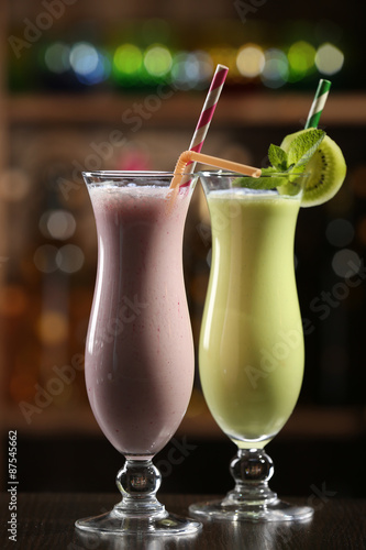 Glasses of fruit cocktails in bar on bright blurred background