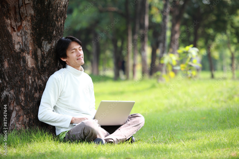 Young man using his laptop on the grass Young man using his laptop on the grass