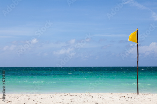 Yellow flag stands on the beach