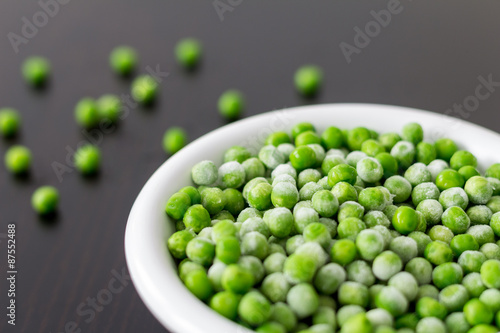 A white bowl with frozen green peas in the kitchen