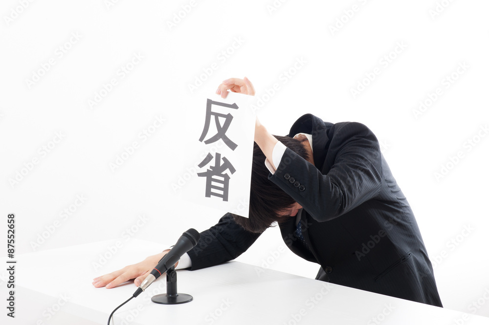 記者会見でマイクを使って謝罪している役員 記者会見でマイクを使って謝罪している役員