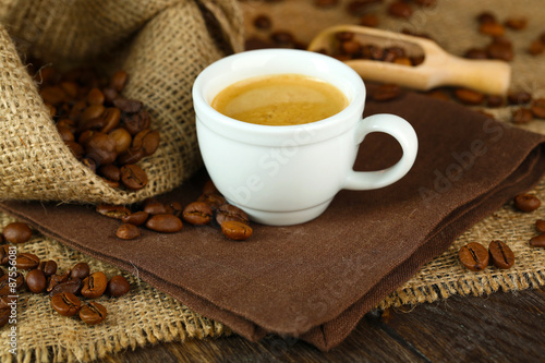 Cup of coffee with beans on table close up