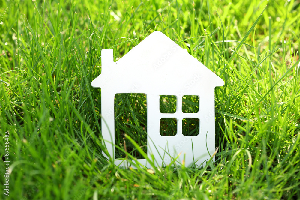 Small model of house over green grass background Small model of house over green grass background