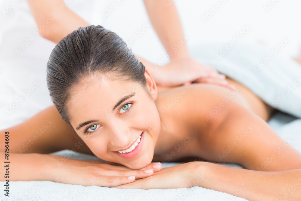 Pretty brunette enjoying a massage smiling at camera 