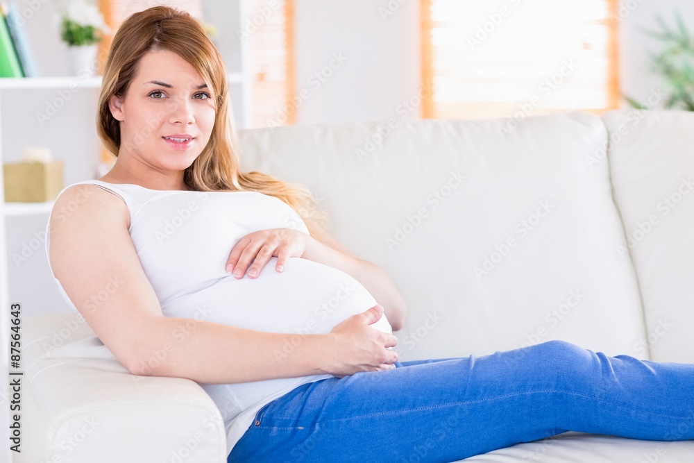 Pregnant woman looking at camera on the couch Pregnant woman looking at camera on the couch