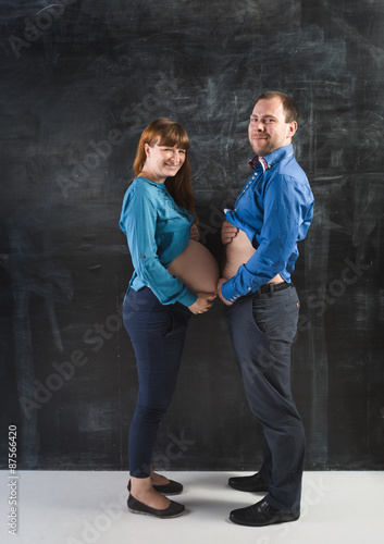 Funny shot of pregnant woman and husband touching by abdomens