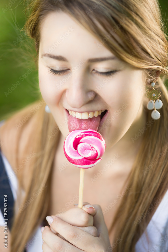 cute girl enjoying licking red twisted lollipop cute girl enjoying licking red twisted lollipop