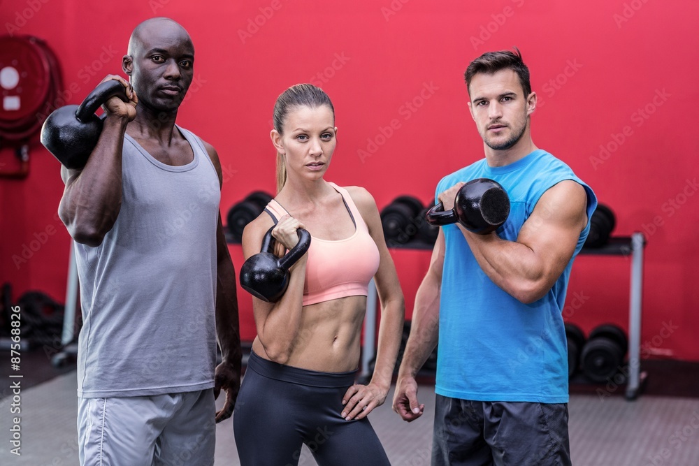 Serious muscular athletes lifting kettlebells Serious muscular athletes lifting kettlebells