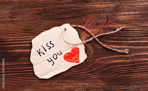 Inscription KISS YOU on cutout carton on wooden background