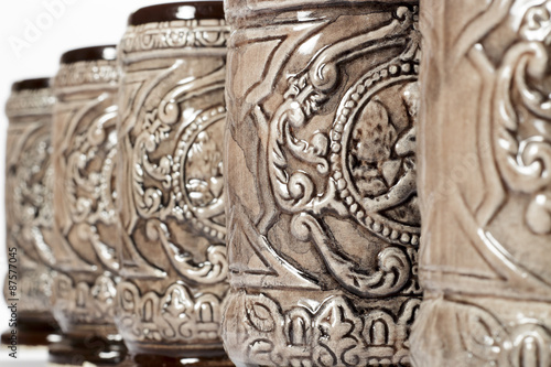 Close-up of decorated pottery tankards placed in row