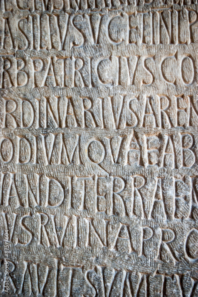 Latin text. Full frame detail of carved latin text on an ancient Roman building. Latin text. Full frame detail of carved latin text on an ancient Roman building.