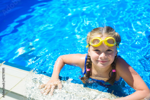 Smiling little girl in swimming goggles in the swimming pool