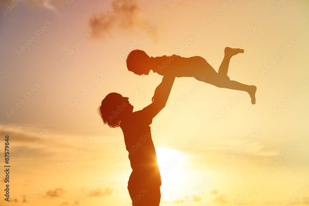 father and little son silhouettes play at sunset