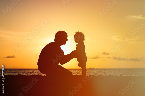 Father and little daughter silhouettes holding hands at sunset