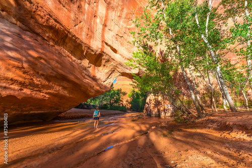 Girl Backpacker walking under Natural Bridge Arch Coyote Gulch photo