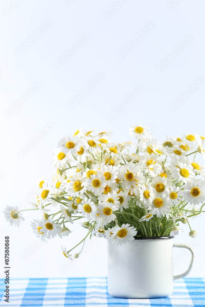 Beautiful bouquet of daisies in cup on light background