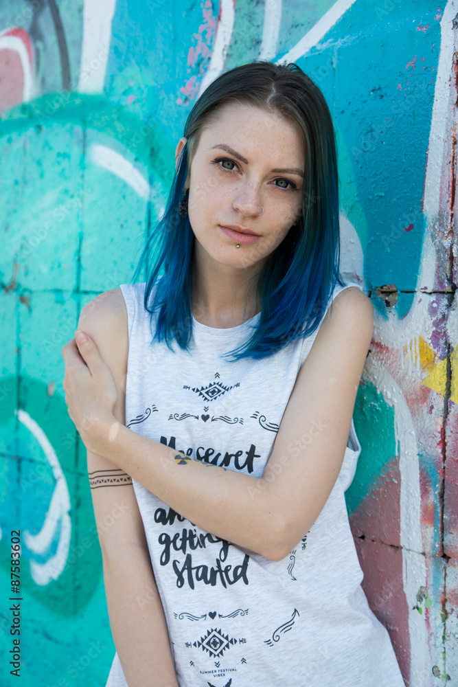 Naklejka premium Young beautiful girl agains graffiti wall