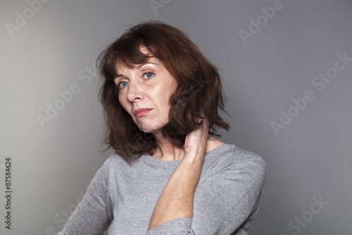 disillusioned mature woman with brown hair and grey sweater thinking,looking bored and concerned