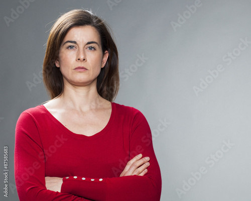 Принти на полотні serious young woman with brown hair and red sweater staring with arms crossed fo