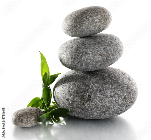 Stack of spa stones with green leaves isolated on white