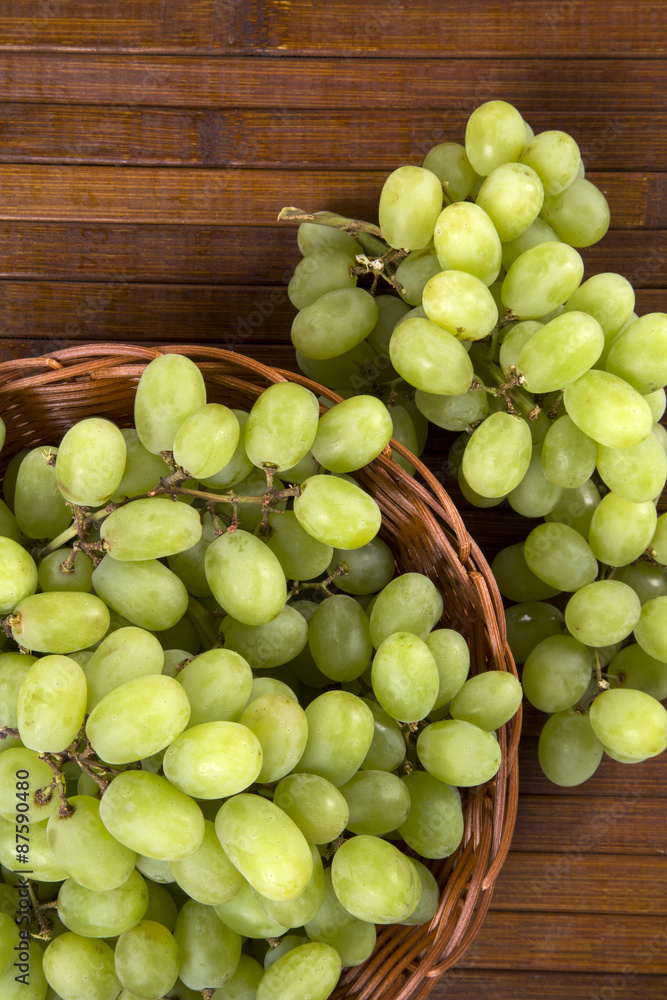 Green grapes in a basket over a wooden surface on a grape field Green grapes in a basket over a wooden surface on a grape field