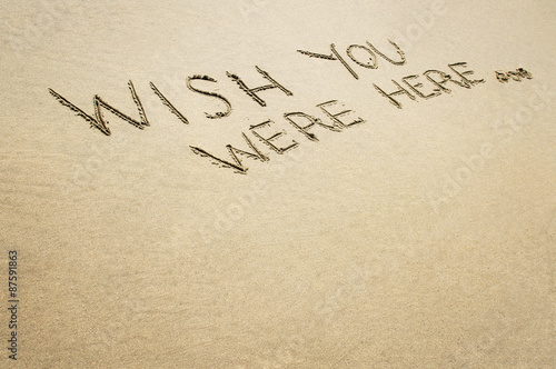 Valokuva Words wish you were here written in the sand on the beach.