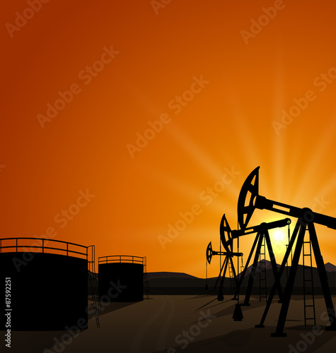 Oil pump jack for petroleum and reserve tanks on sunrise backgro