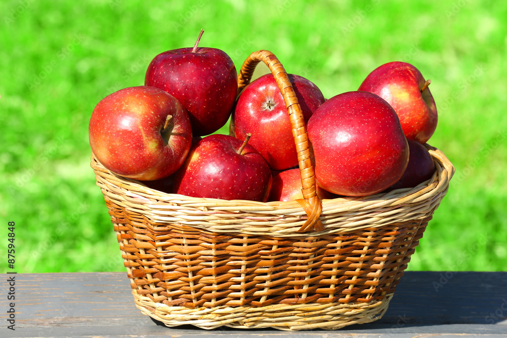Ripe red apples in wicker basket outdoors Ripe red apples in wicker basket outdoors