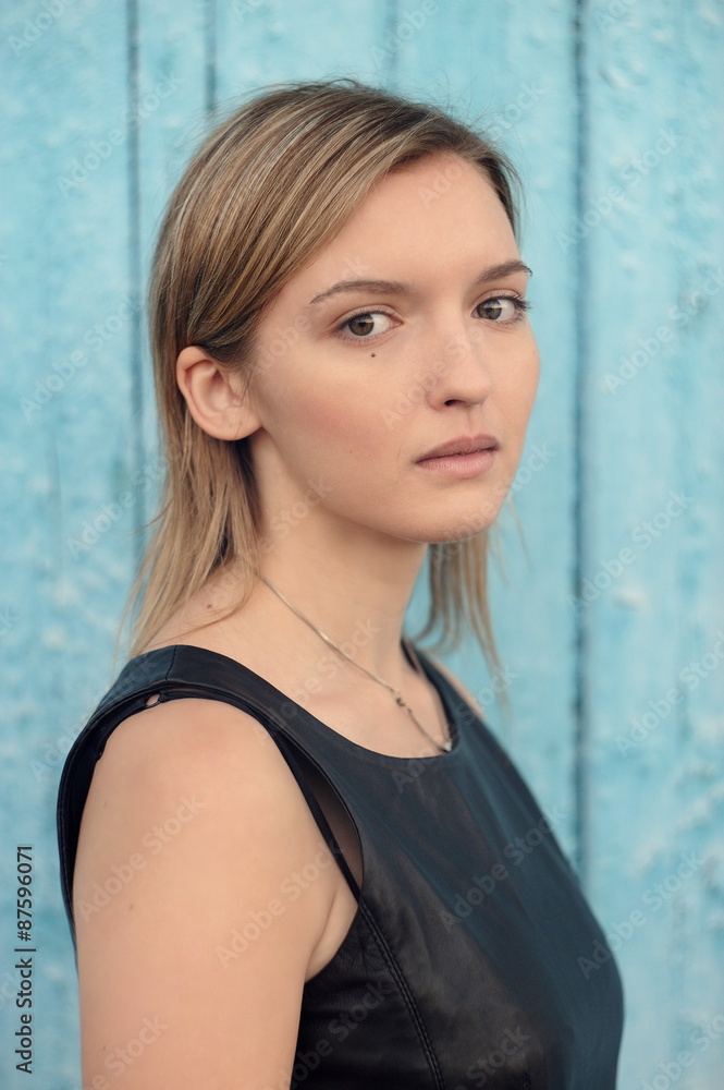 Fototapeta premium Young shy blonde brown-eyed girl with long straight hair in blac