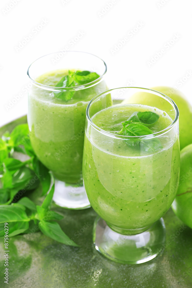 Glasses of green healthy juice with basil and apples on metal tray close up Glasses of green healthy juice with basil and apples on metal tray close up