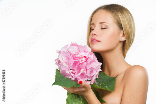 Portrait of young beautiful woman with a healthy clean skin smelling delicate pink flower, isolated on white background