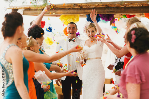Fotografija beautiful  gorgeous blonde bride  and stylish groom under confetti, hawai  color