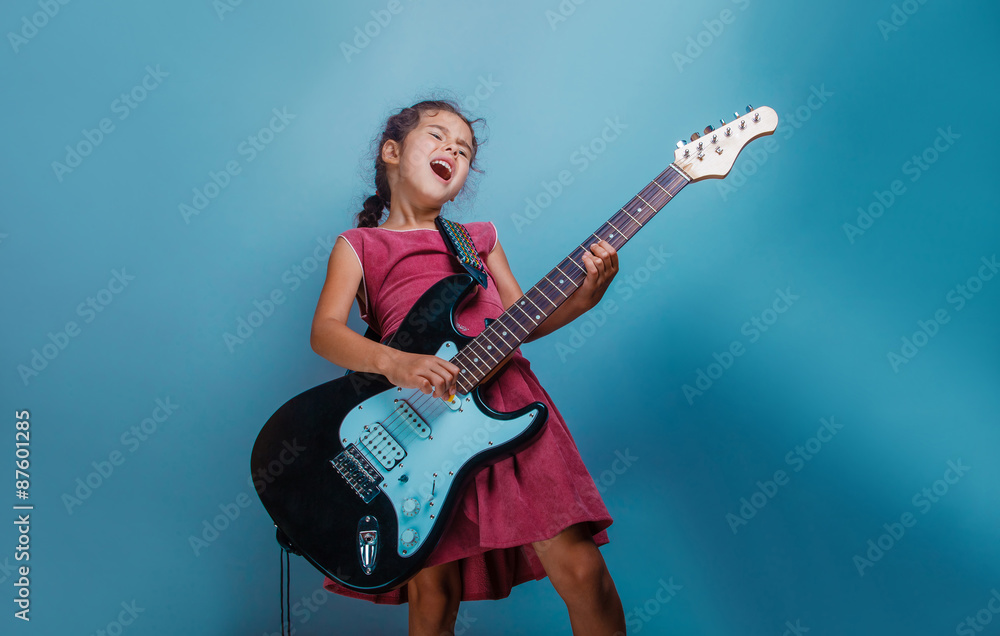 Girl European appearance ten years playing guitar on a blue bac Girl European appearance ten years playing guitar on a blue bac