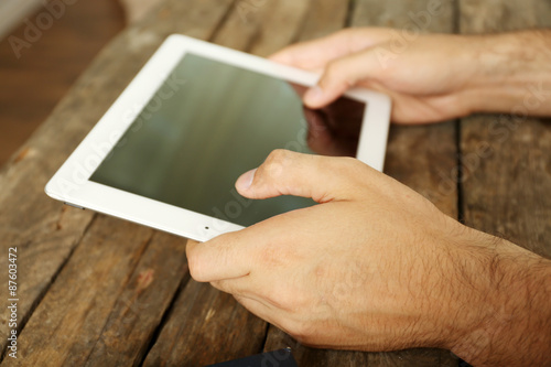 Hands holding digital tablet on wooden table background