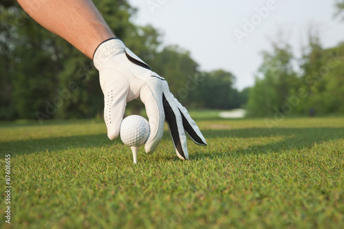 Foto Selective foccus of golfer's hand placing ball on tee