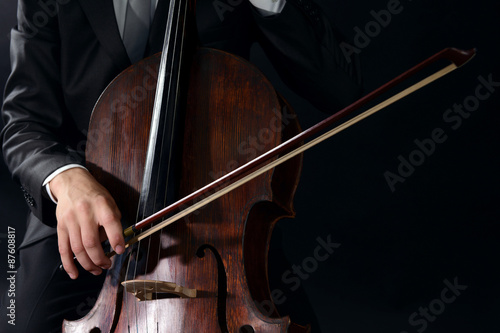 Man playing on cello on dark background