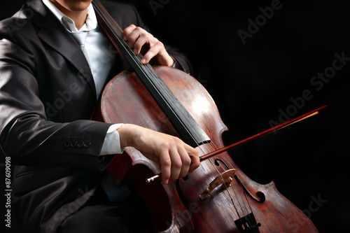 Man playing on cello on dark background